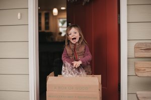 Girl getting home delivery of box of good organic local home delivery of produce in seattle washington